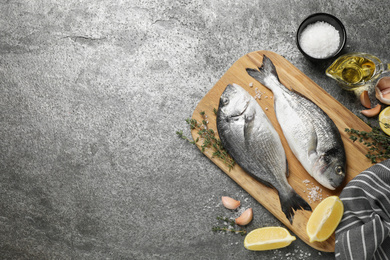 Photo of Flat lay composition with raw dorada fish on grey table, space for text
