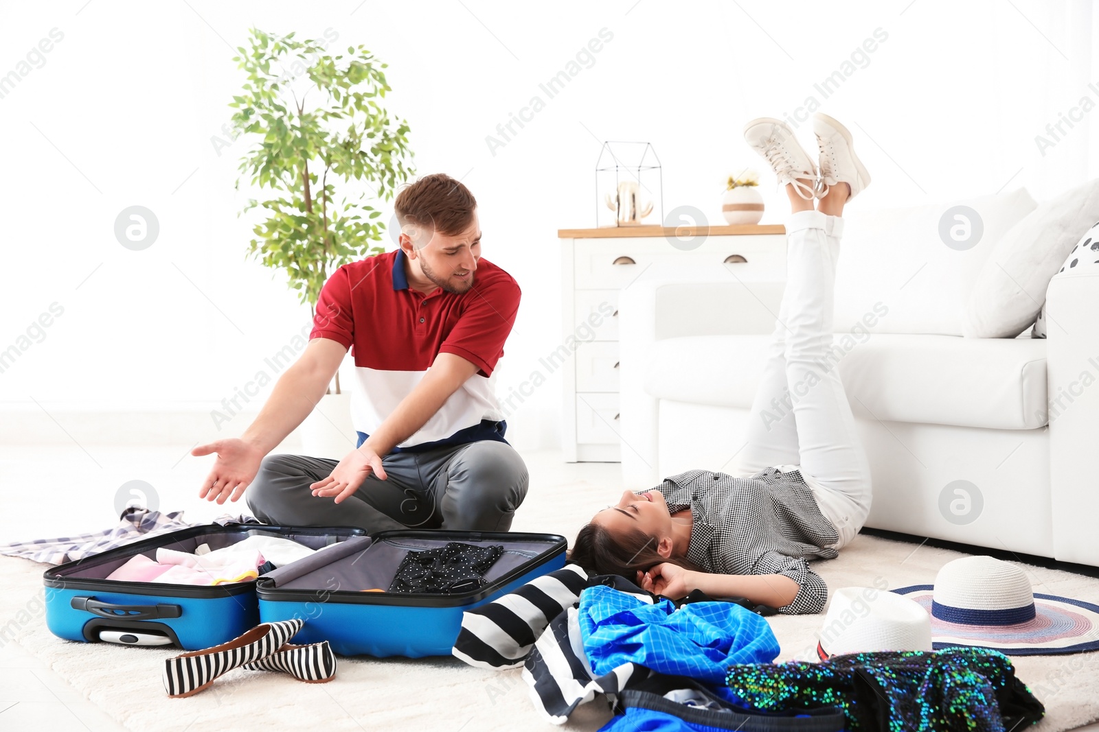 Photo of Young couple packing suitcase for summer journey at home