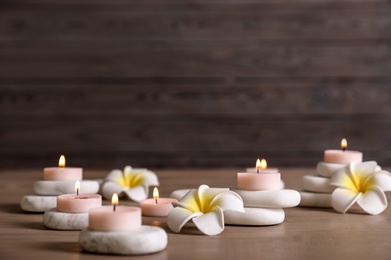 Composition of spa stones, flowers and burning candles on wooden table