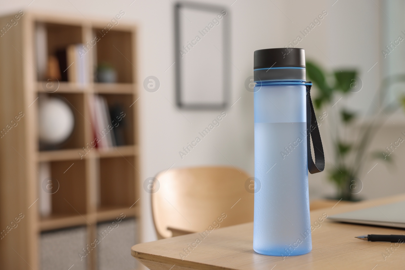 Photo of Transparent bottle at wooden table indoors, space for text