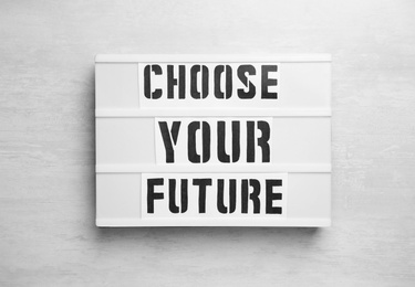 Photo of Board with words CHOOSE YOUR FUTURE on white wooden background, top view. Career concept