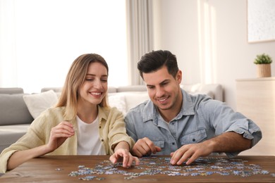 Happy couple playing with puzzles at home