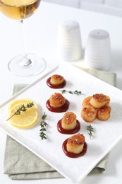 Photo of Delicious fried scallops with tomato sauce and lemon served on white table