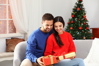 Photo of Happy young couple with Christmas gifts at home