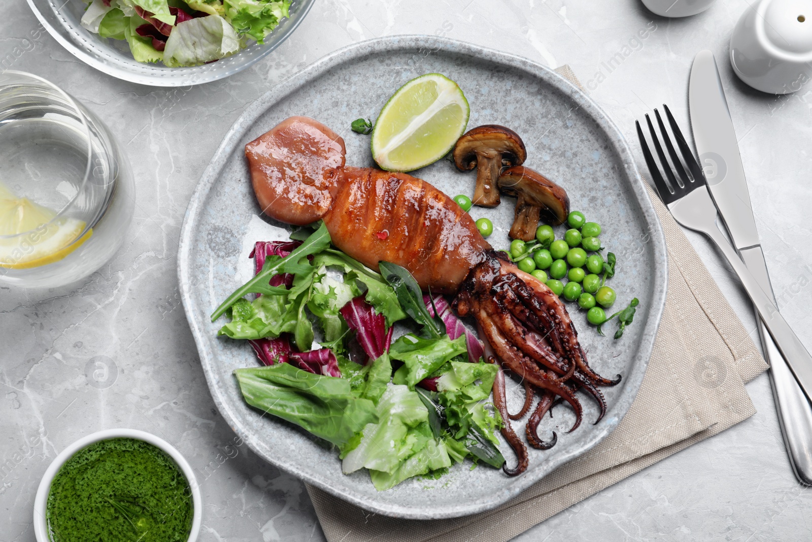 Photo of Tasty grilled squid served on white marble table, flat lay