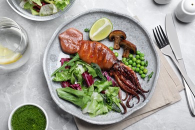 Tasty grilled squid served on white marble table, flat lay