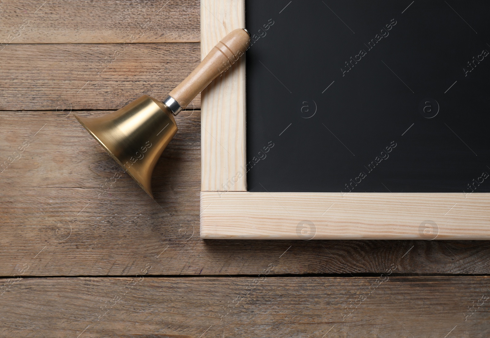 Photo of Golden bell and blackboard on wooden background, flat lay. School days