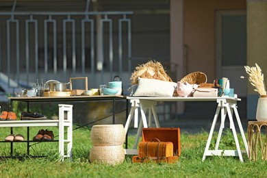 Small tables with many different items on garage sale in yard