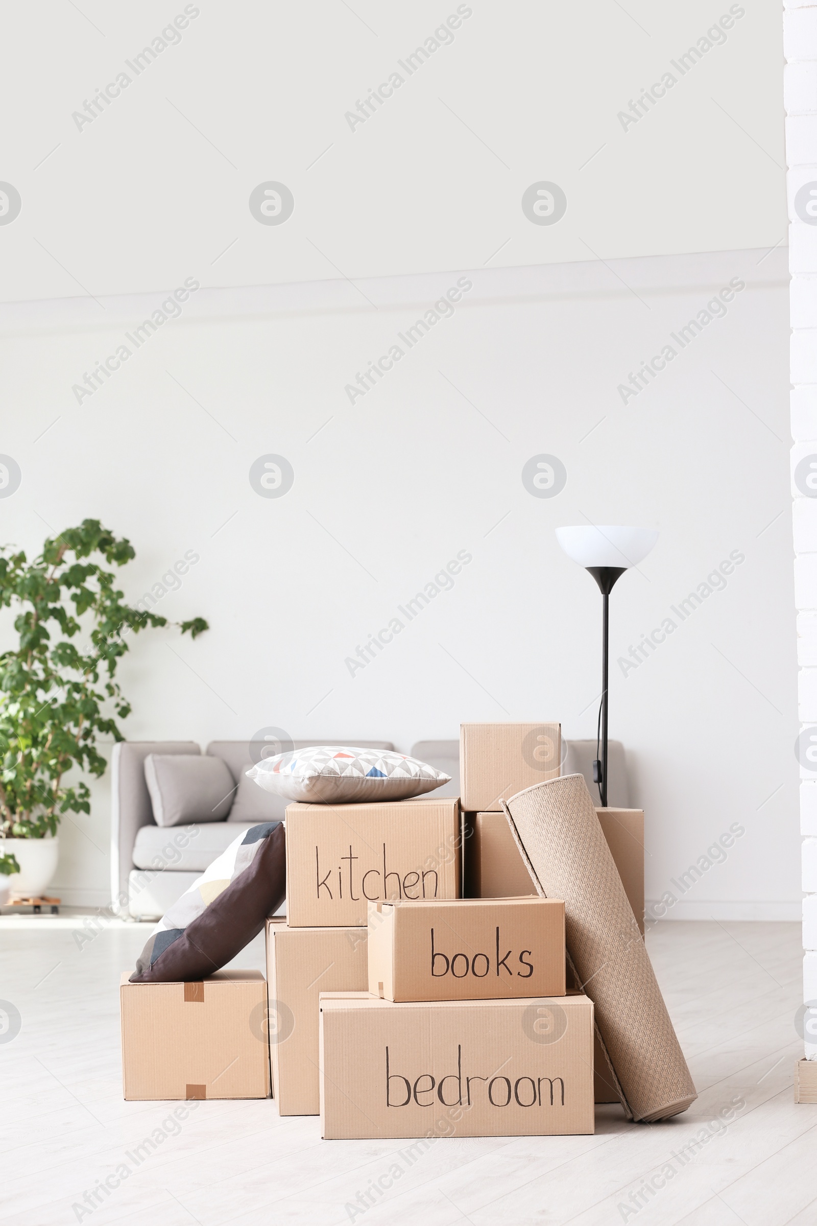 Photo of Pile of moving boxes and household stuff in living room