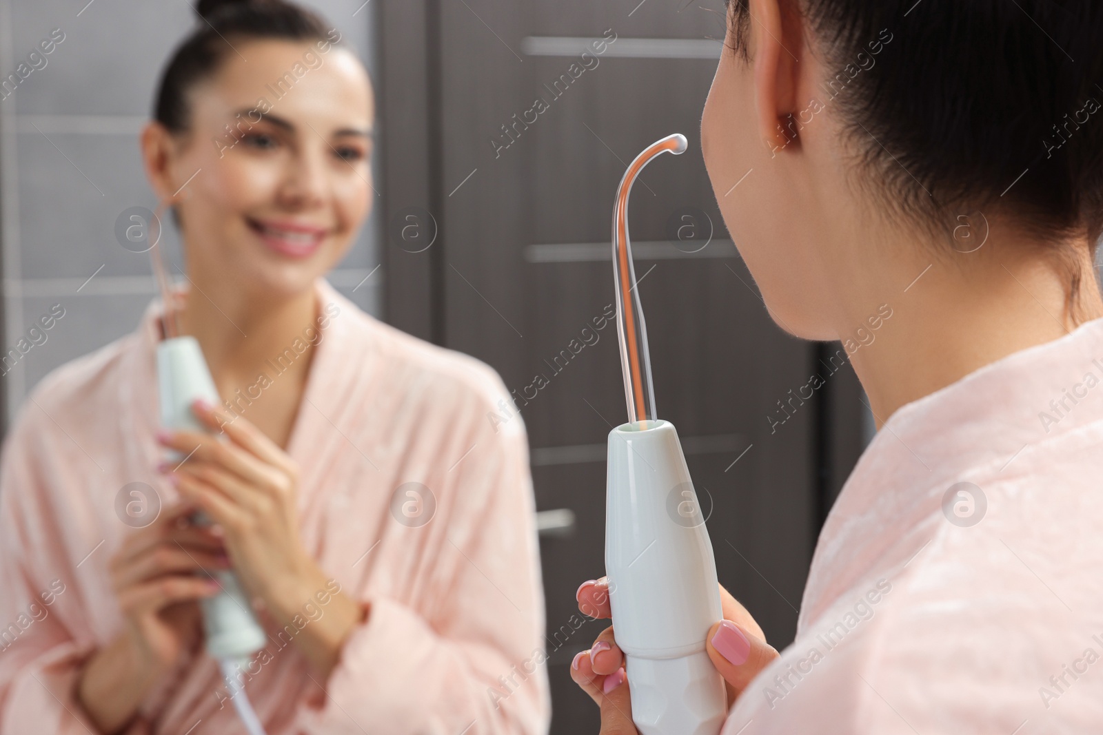 Photo of Woman using high frequency darsonval device near mirror in bathroom, closeup. Space for text