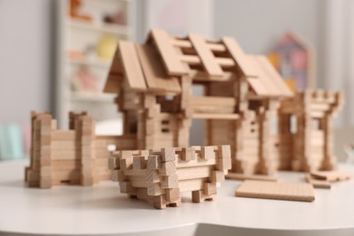 Photo of Wooden entry gate and building blocks on white table indoors, selective focus. Children's toy