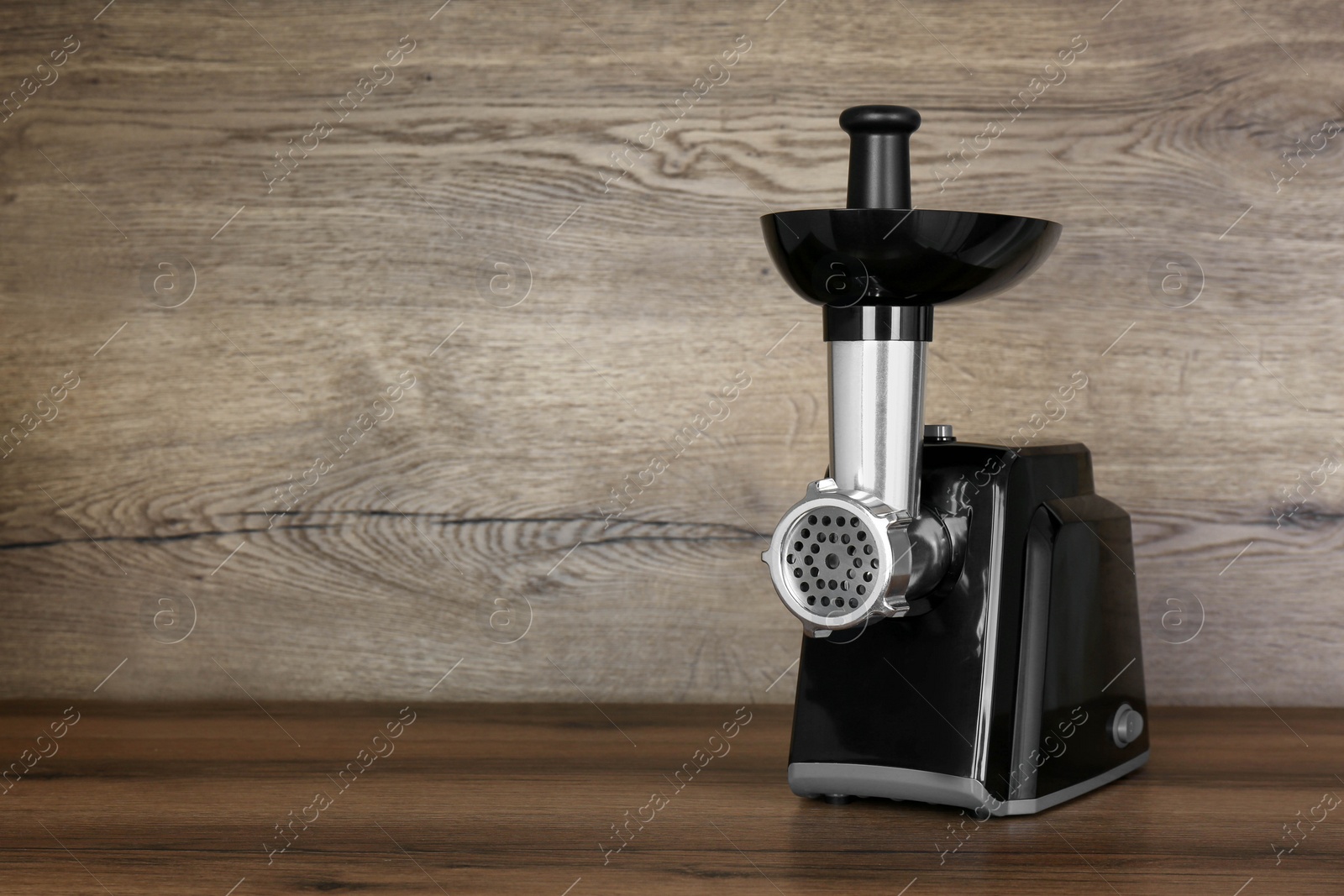 Photo of Modern electric meat grinder on wooden table. Space for text