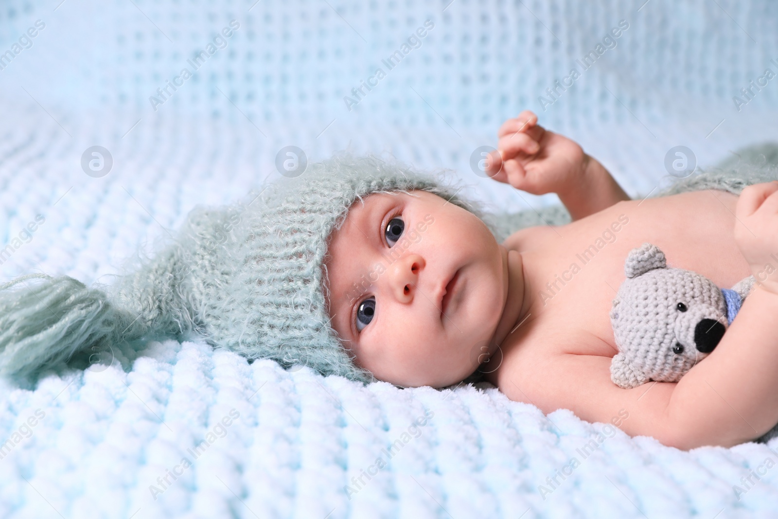 Photo of Cute newborn baby with crochet toy on light blue blanket