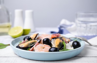 Plate of delicious salad with seafood on white wooden table