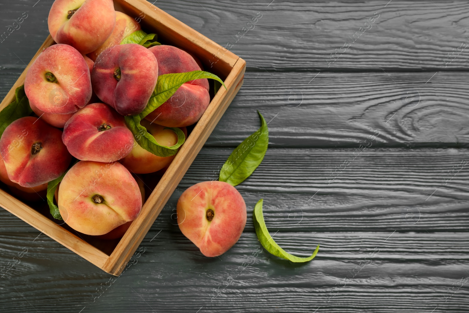 Photo of Fresh ripe donut peaches on grey wooden table, flat lay. Space for text