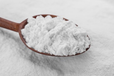 Photo of Heap of natural starch and wooden spoon, closeup