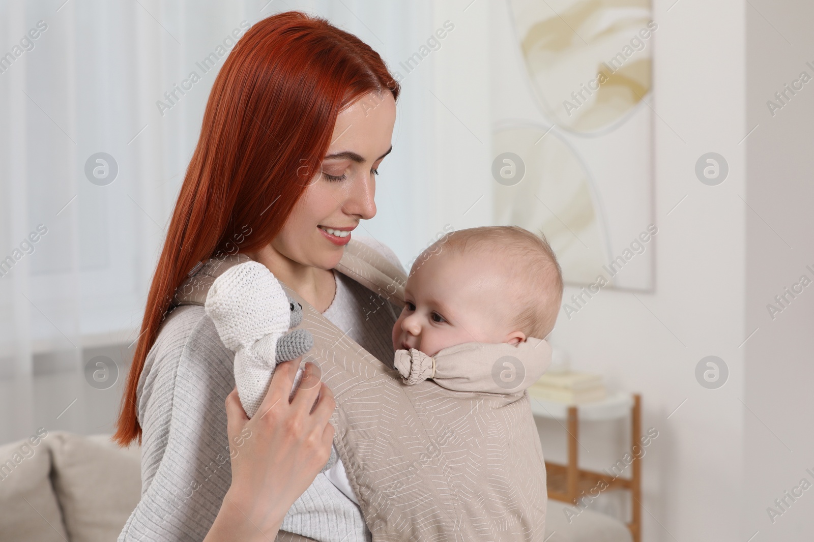 Photo of Mother holding her child in sling (baby carrier) at home