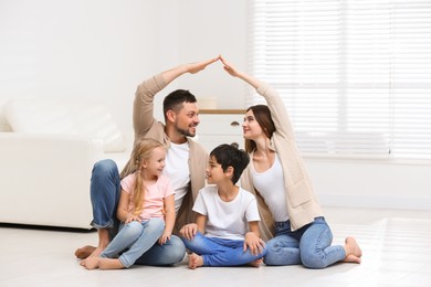 Photo of Happy family forming house roof with their hands at home. Insurance concept