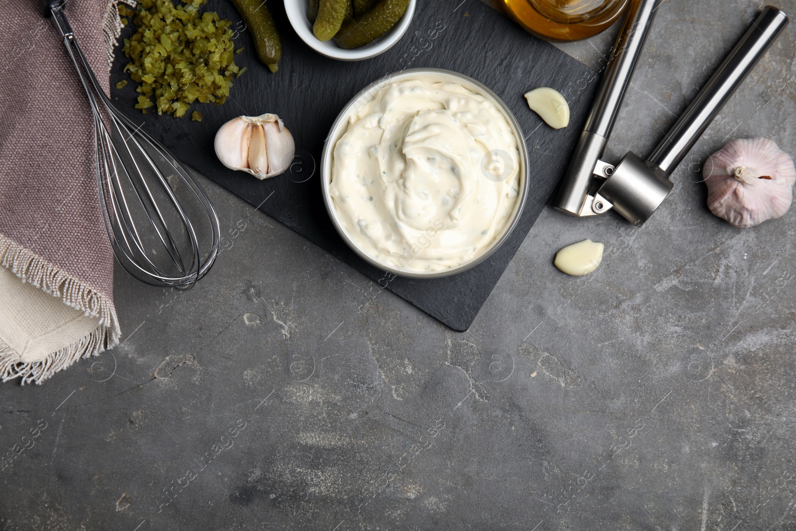 Photo of Tasty tartar sauce and ingredients on grey table, flat lay. Space for text