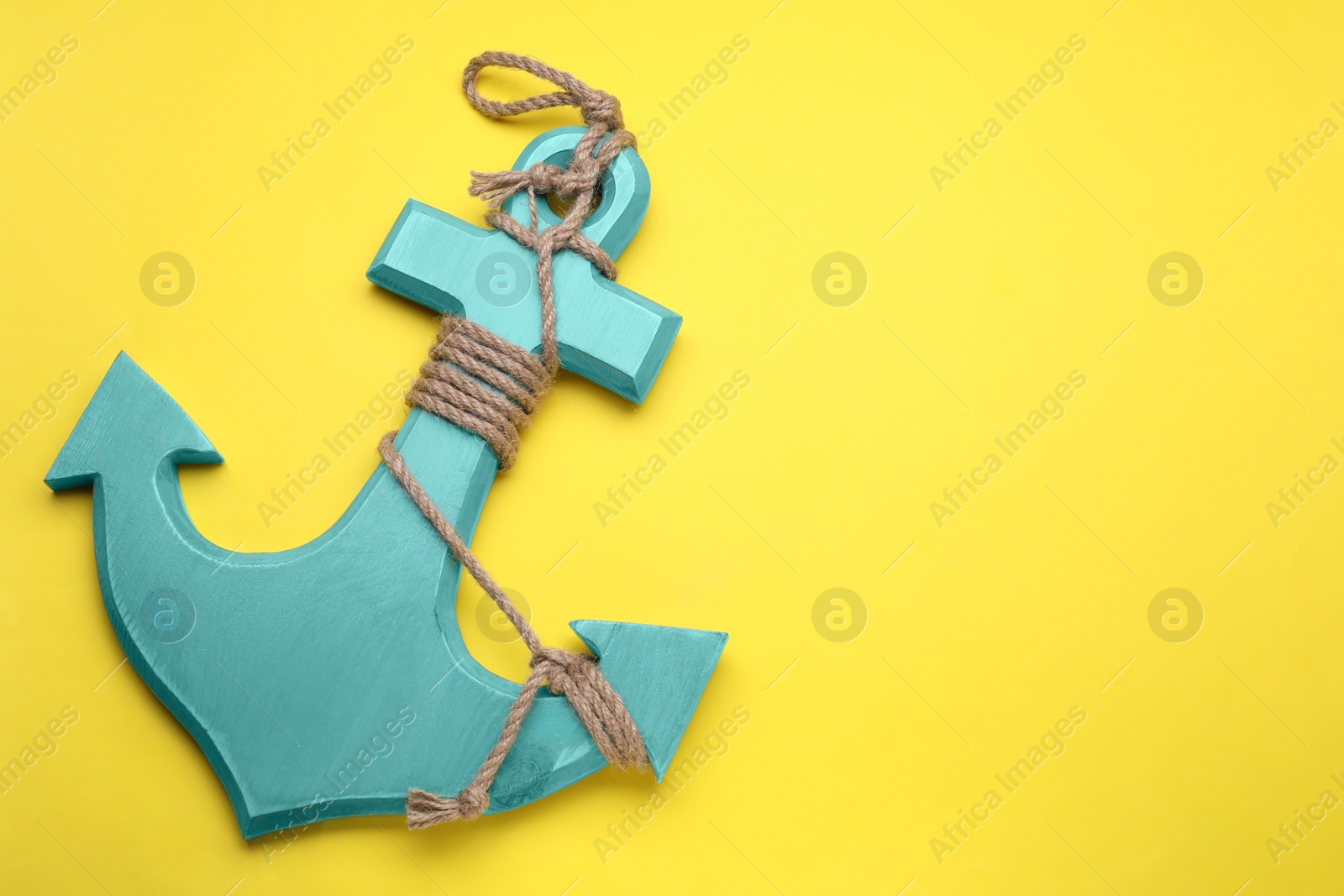 Photo of Wooden anchor figure on yellow background, top view. Space for text