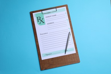 Photo of Clipboard with medical prescription form and pen on light blue background, top view