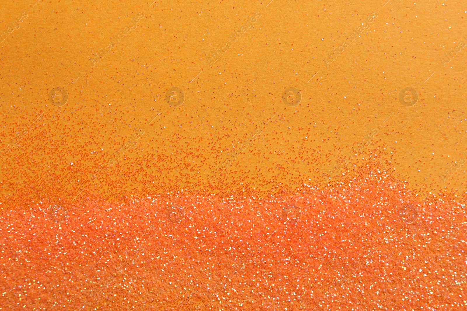 Photo of Shiny bright glitter on orange background, flat lay. Space for text