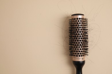 Photo of Professional brush with lost hair on beige background, top view. Space for text
