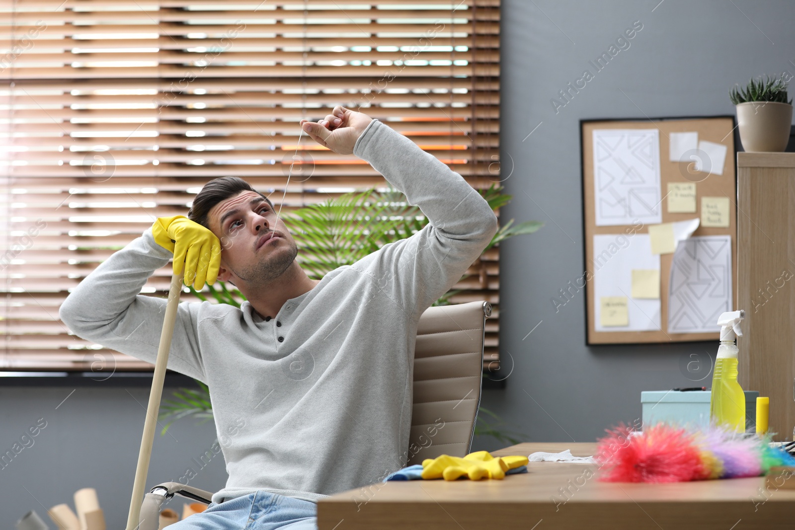 Photo of Lazy man procrastinating while cleaning at home