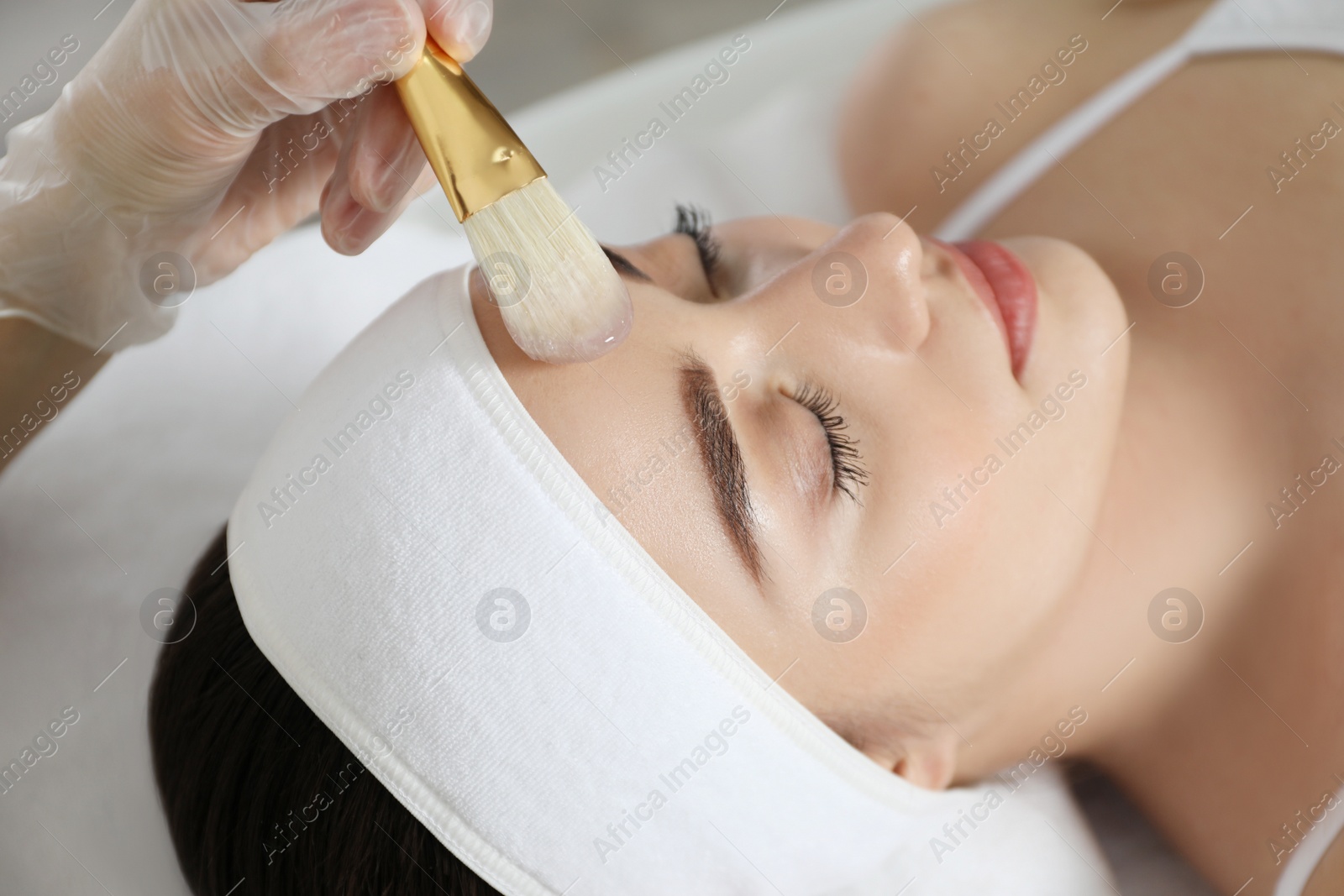 Photo of Young woman during face peeling procedure in salon