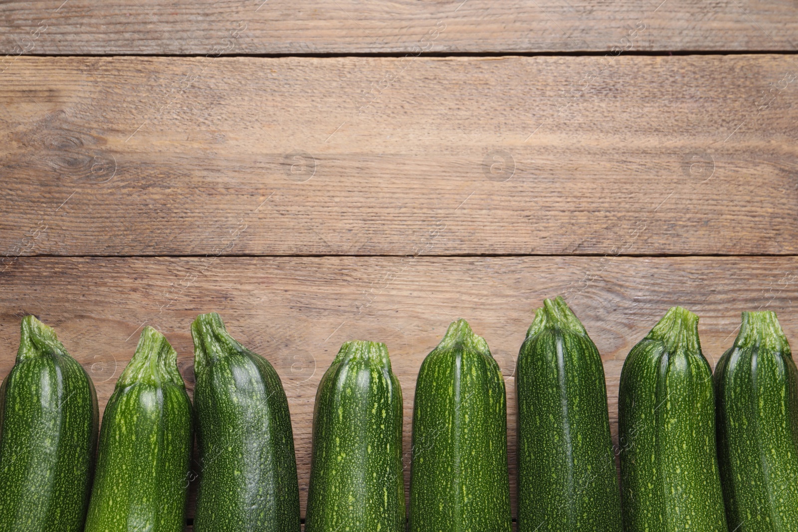 Photo of Raw ripe zucchinis on wooden table, flat lay. Space for text