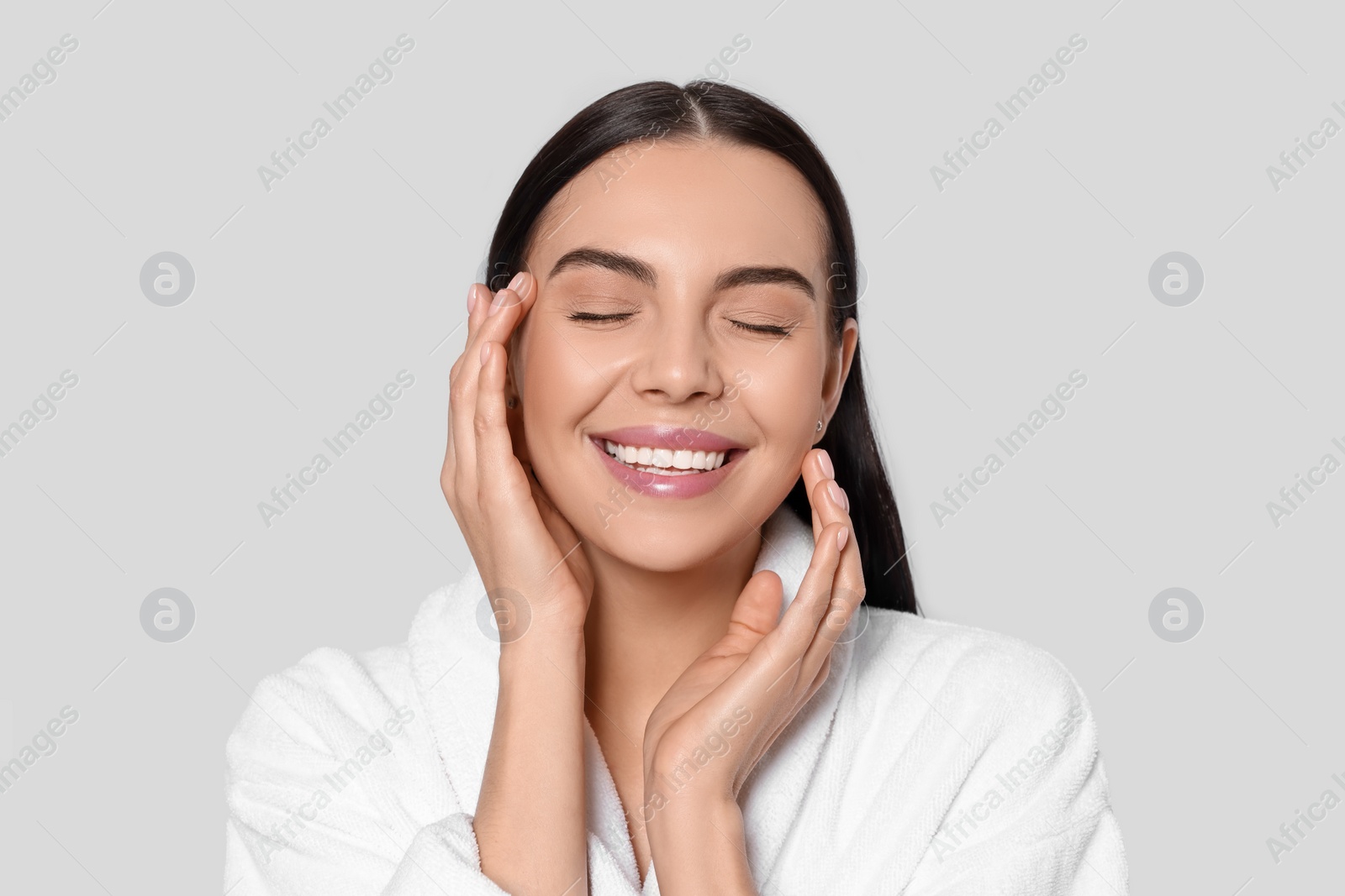 Photo of Portrait of attractive young woman in bathrobe on light grey background. Spa treatment