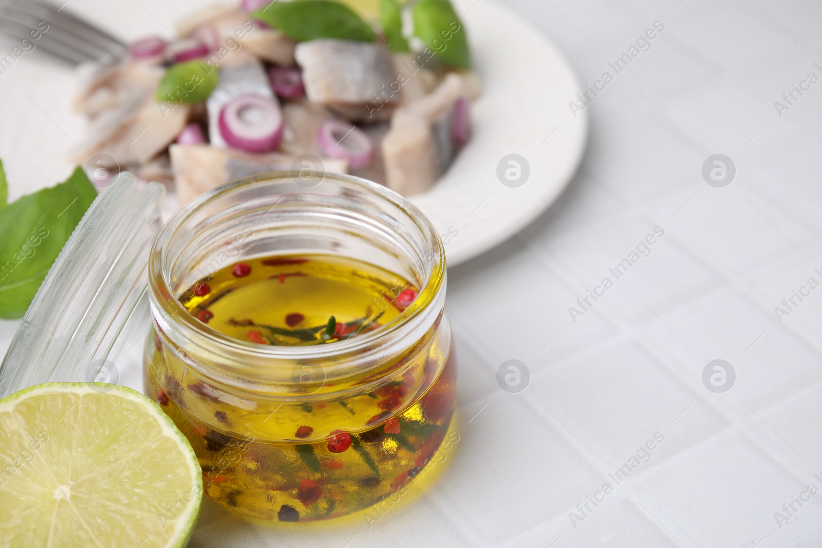 Photo of Tasty fish marinade in jar on light tiled table, closeup. Space for text