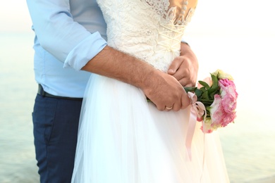 Wedding couple with beautiful bouquet on beach