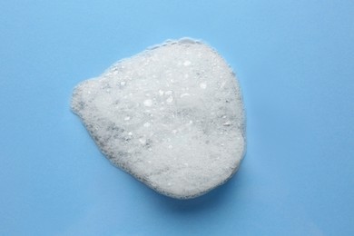 Photo of Drop of bath foam on light blue background, top view