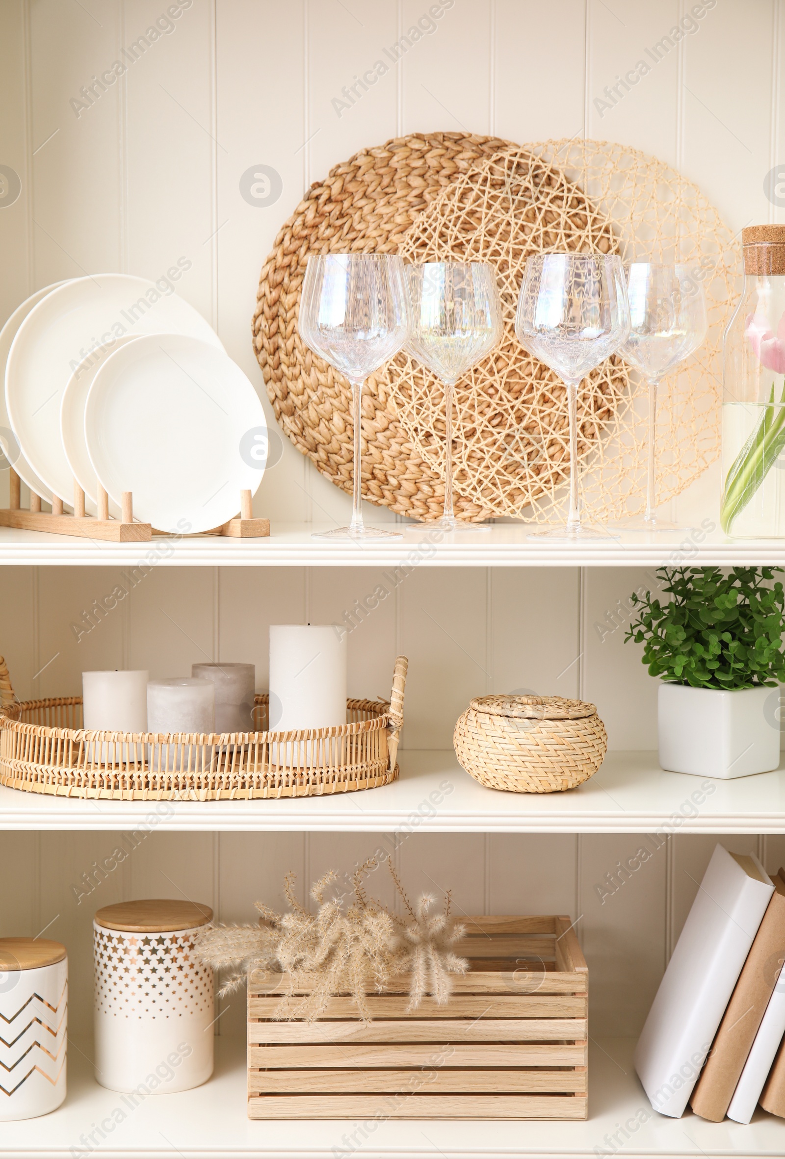 Photo of White shelving unit with dishware and different decorative stuff