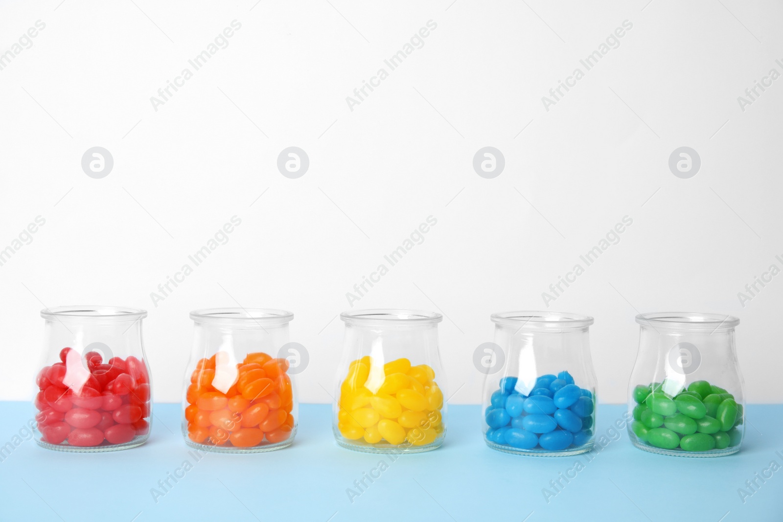 Photo of Jars of colorful jelly beans on table. Space for text