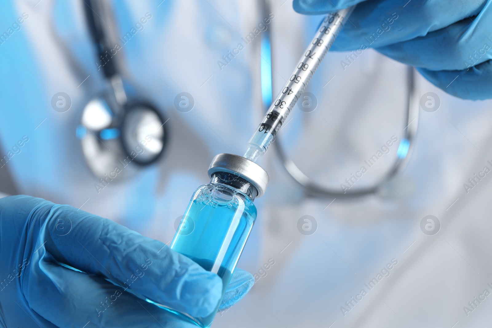 Photo of Doctor filling syringe with medication from glass vial, closeup