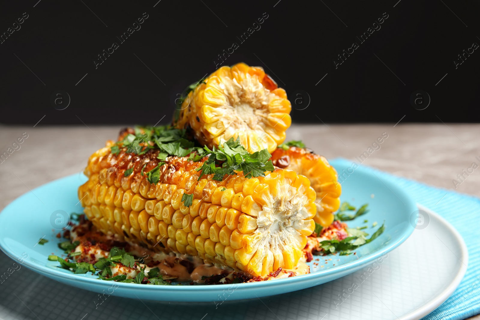 Photo of Plate with delicious grilled corn cobs and parsley on table