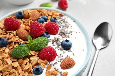 Tasty homemade granola with yogurt and berries on light grey table, closeup. Healthy breakfast