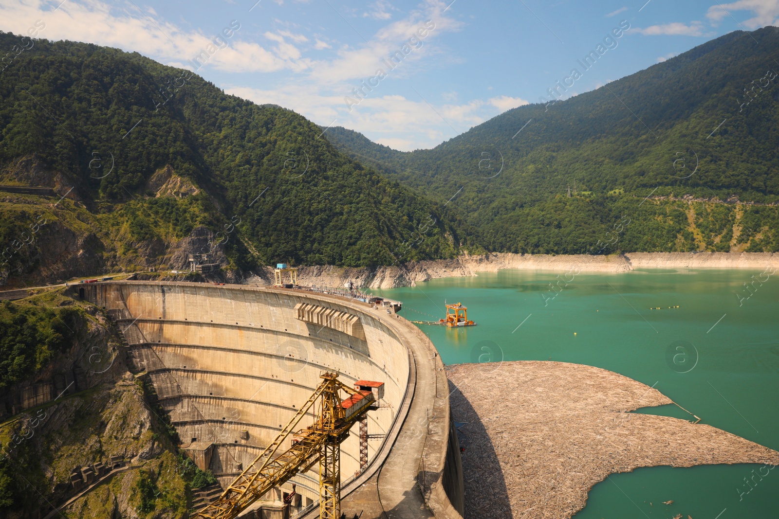 Photo of BATUMI, GEORGIA - AUGUST 13, 2022: Tower crane and hydroelectric power station in mountains