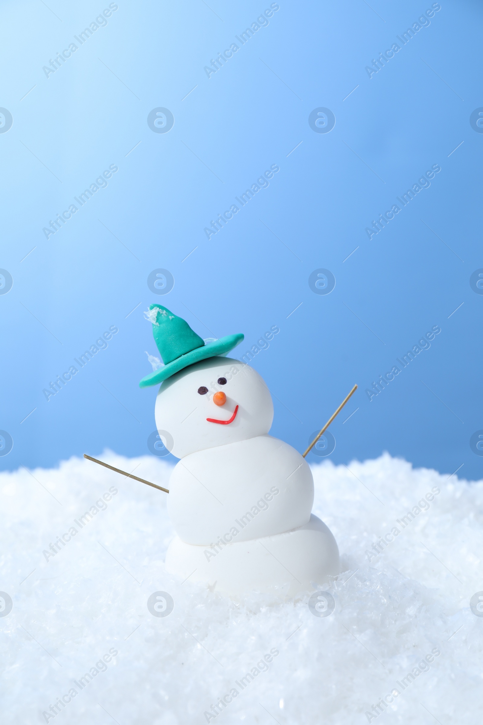 Photo of Funny snowman on snow against light blue background, space for text