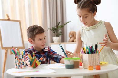 Little children painting hands at table indoors