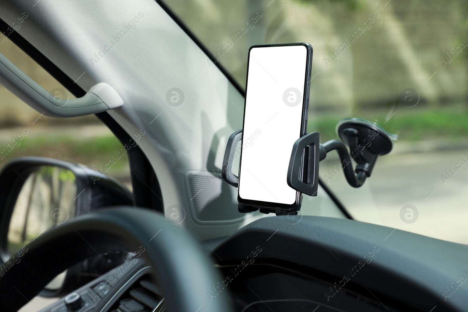 Photo of Car holder with modern mobile phone on windshield of automobile. Mockup for design