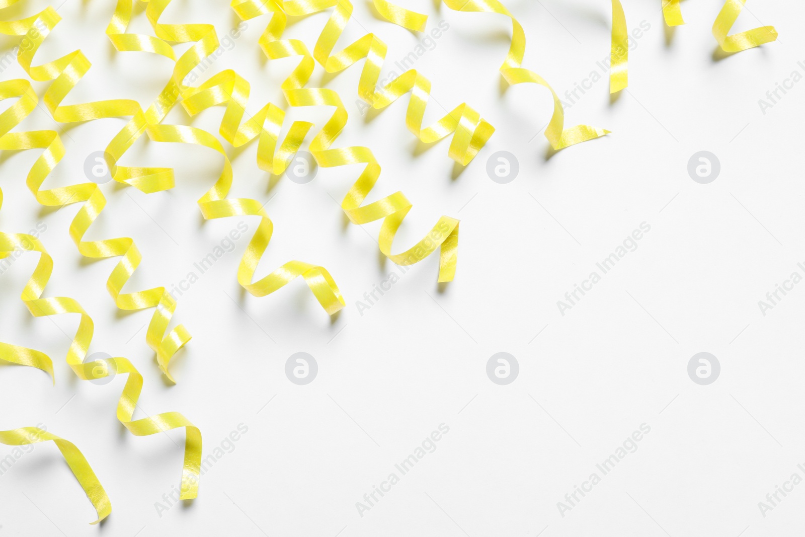 Photo of Many yellow serpentine streamers on white background