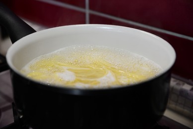 Photo of Cooking pasta in saucepan on stove, closeup