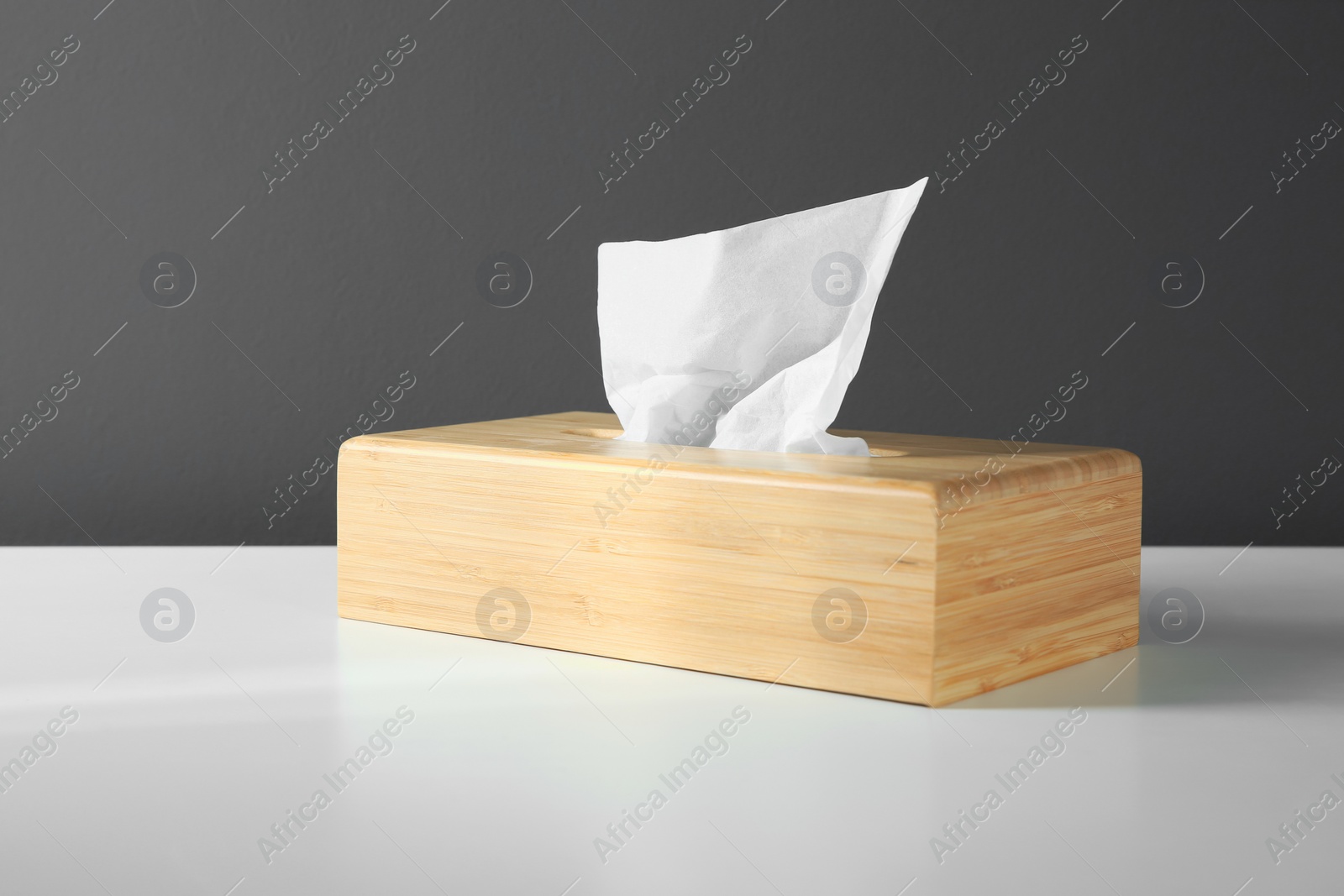 Photo of Wooden holder with paper tissues on white table