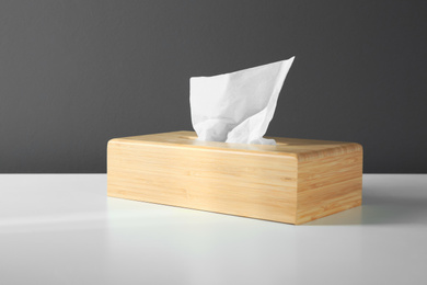 Photo of Wooden holder with paper tissues on white table