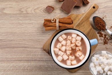 Photo of Cup of aromatic hot chocolate with marshmallows and cocoa powder served on wooden table, flat lay. Space for text