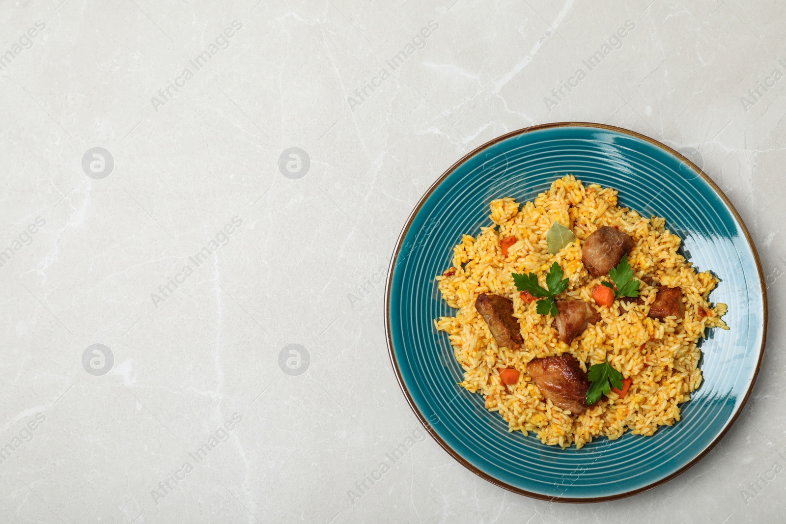 Photo of Plate of delicious rice pilaf on light background, top view with space for text