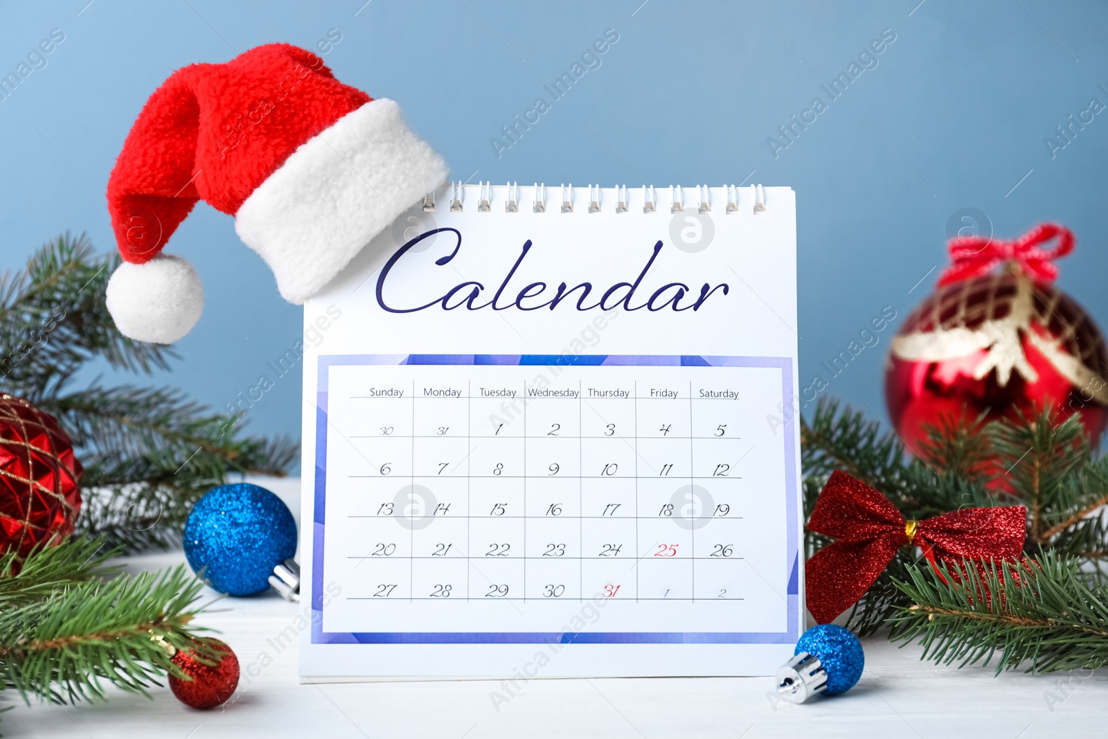 Photo of Flip calendar with Santa hat and Christmas decor on white wooden table. Holiday countdown